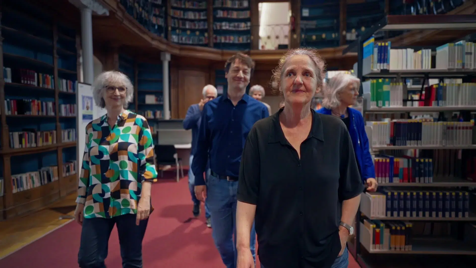 Ute Schmid geht mit einer Gruppe durch eine historische Bibliothek der Universität Bamberg; Szene aus dem Porträtfilm über die Communicator-Preisträgerin Prof. Dr. Ute Schmid für die DFG. Produziert von Sterntaucher Filmproduktion.